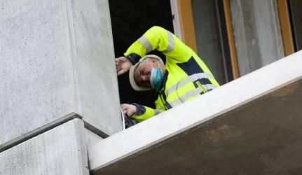 Statybininkai žmones stumia po mašinomis